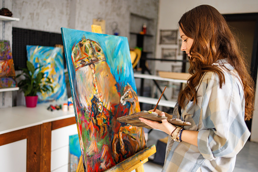 Beautiful woman painting in art studio