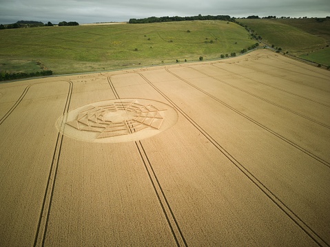 An aerial view of crop circles in a vast agricultural field in the countryside of Wiltshire, England