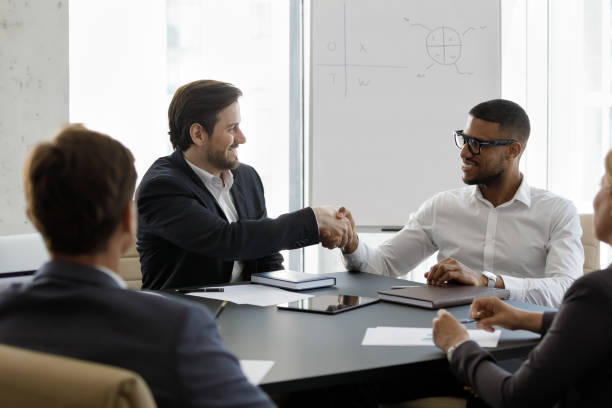 istock happy diverse partners shaking hands in modern office. 1418192877