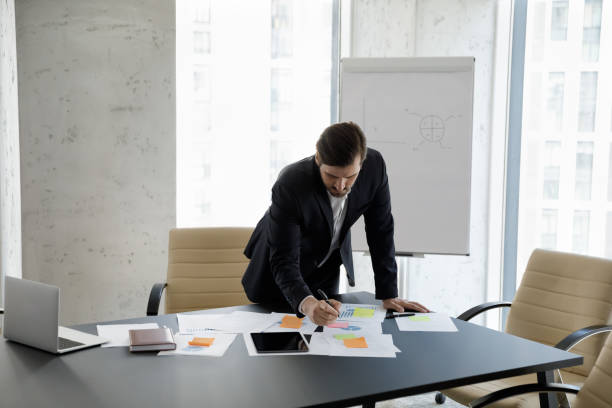 istock Serious young 35s businessman managing workflow with colored stickers. 1418192885