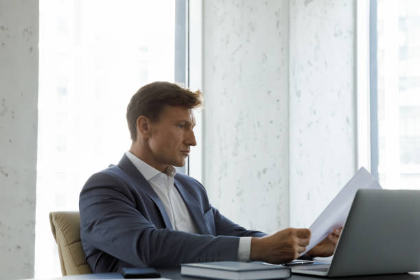 istock Focused skilled middle aged 40s businessman reading document. 1418192935