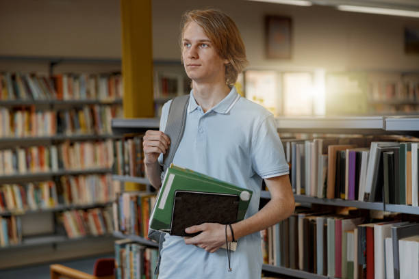 istock Smart male student chooses book while standing in the university library 1418194686