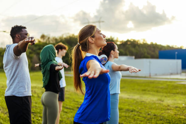 istock Yoga instructor and young friends in park working out 1418197440