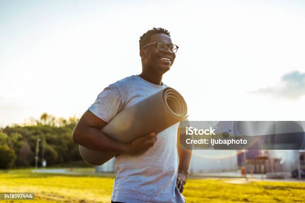 African American Man Holding Yoga Mat Smiling On Sunny Day Stock Photo - Download Image Now