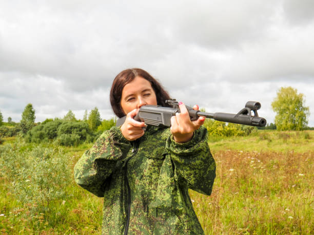 istock A young beautiful woman in protective military uniforms with a rifle in her hands 1418201218