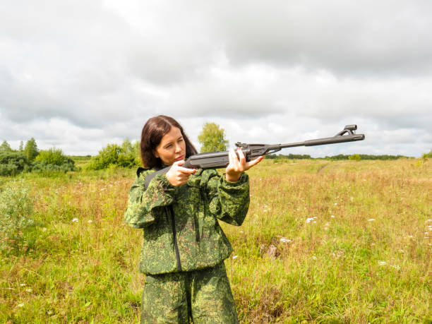 istock A young beautiful woman in protective military uniforms with a rifle in her hands 1418201250