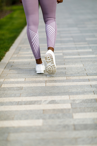 Female Athlete is Walking Down in the City Streets in Sports Sneakers.