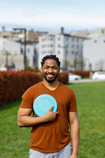 Handsome African Man is Holding a Frisbee and Looking and Smiling to the Camera.