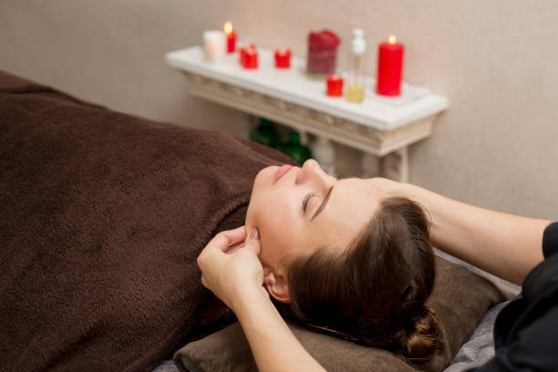Facial massage in the spa. Beautician does facial massage. Body and face care stock photo