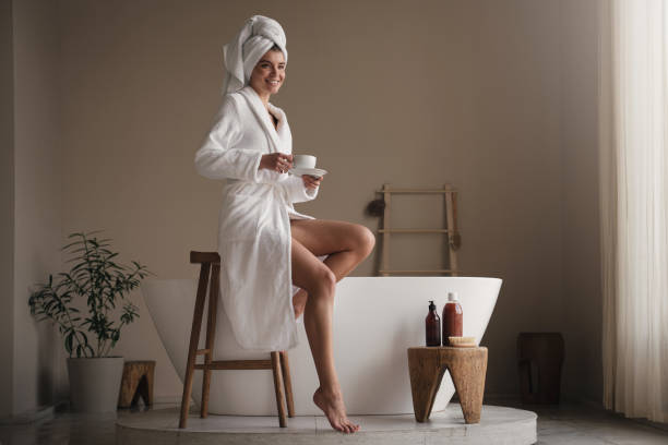 ritratto di donna in accappatoio con tazza di bevanda calda rilassante dopo le procedure termali - bathrobe women cup towel foto e immagini stock