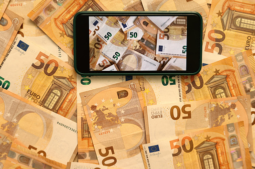 Money paper 50 euro banknotes on the background of a smartphone screen, the concept of business, investment and income growth. Mobile banking and finance concept.