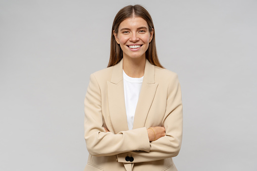Portrait of self-confident successful business coach with crossed arms isolated on gray studio background