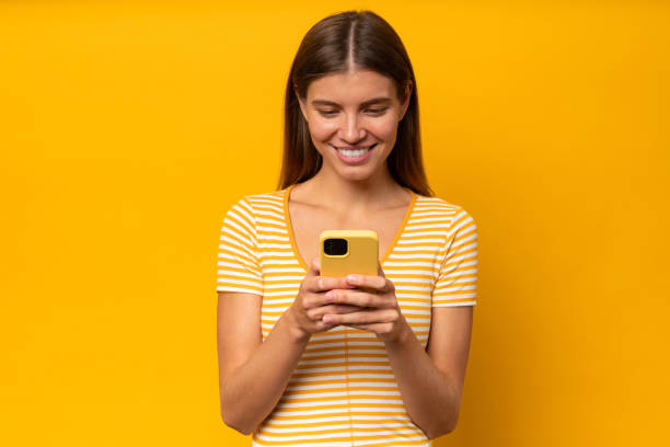istock Woman using app on phone, looking at screen with joy, isolated on yellow background 1418213095