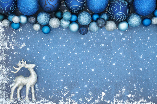 Christmas background with reindeer ornament and sparkling blue tree decorations on grunge. Festive magical north pole cold winter theme for the holiday season