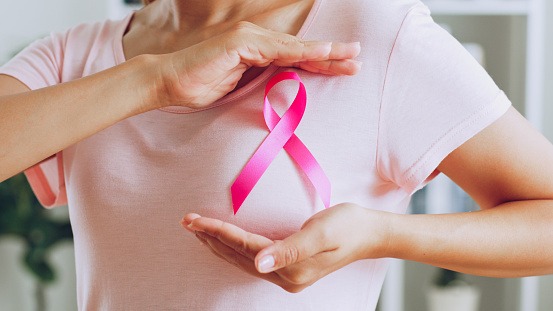 Mujer asiática muestra cinta rosa como señal del mes de concientización sobre el cáncer de mama en octubre photo
