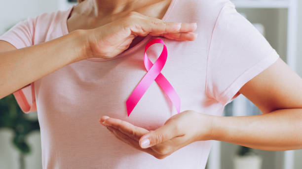 Asian woman show pink ribbon as sign of October Breast Cancer Awareness month stock photo