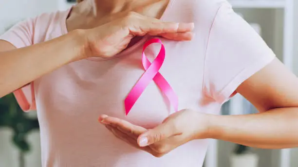Photo of Asian woman show pink ribbon as sign of October Breast Cancer Awareness month