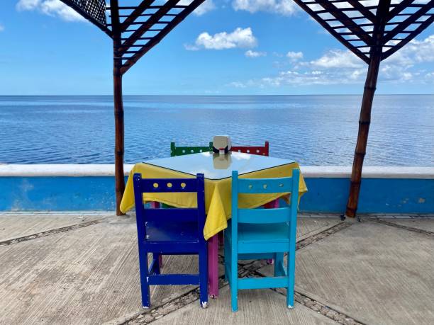 istock Empty table with colourful chairs looking over the sea 1418215128