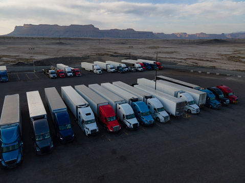 Semi Truck Lorries Lined Up for the Evening in a Large Parking Lot at a Truck Stop in the Desert Area of Eastern Utah on I-70 At Dusk Under a Dramatic Cloudscape Sunset Sky