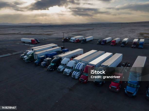 Semi Truck Lorries Lined Up For The Evening In A Large Parking Lot At A Truck Stop In The Desert Area Of Eastern Utah On I70 At Dusk Under A Dramatic Cloudscape Sunset Sky Stock Photo - Download Image Now