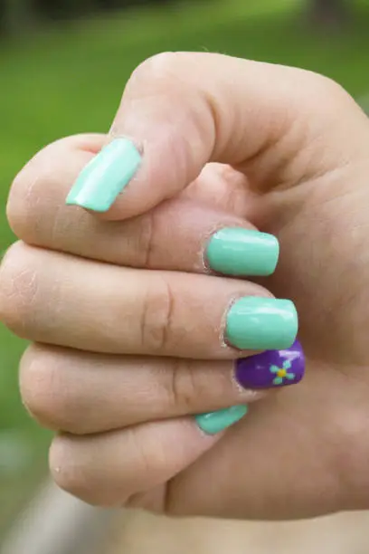 Womans hand with nails painted in green color. Green background