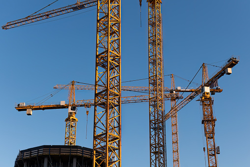 Close up of group of tower cranes against the blue sky in summer