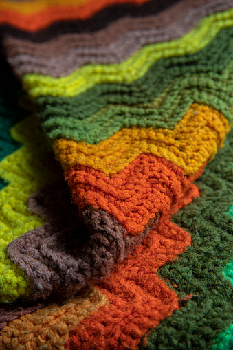 close-up of grandma's crocheted or knitted retro zigzag striped blanket, this blanket makes you think of grandma's house, it is cozy and warm, great for sick days, cold winter mornings, and lazy days on the couch.