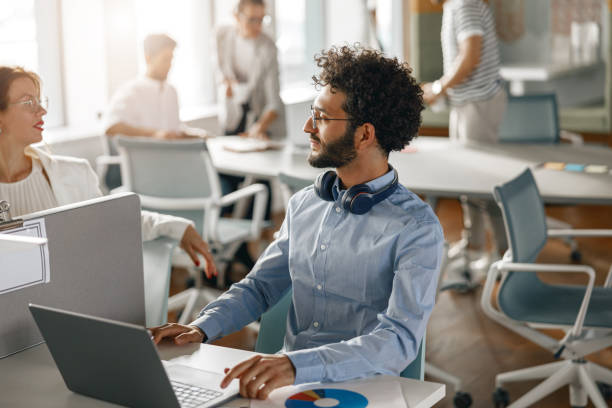 istock Businessman working laptop while sitting in modern office on colleagues background 1418219625