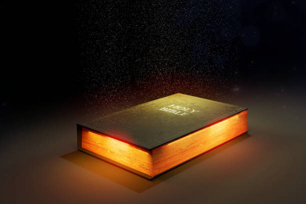 Shining Holy Bible Holy Bible glowing on a dark background. 3D render illustration. bible art library stock pictures, royalty-free photos & images