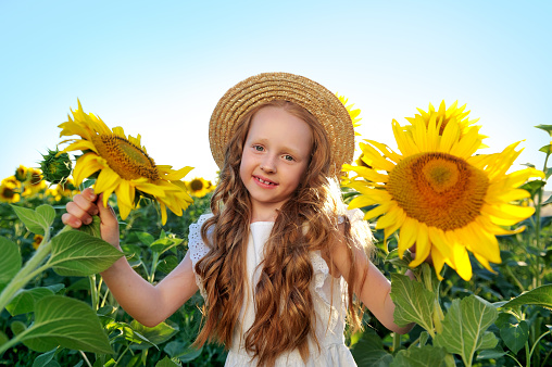 Smiling girl holding blooming sunflowers in both hands
