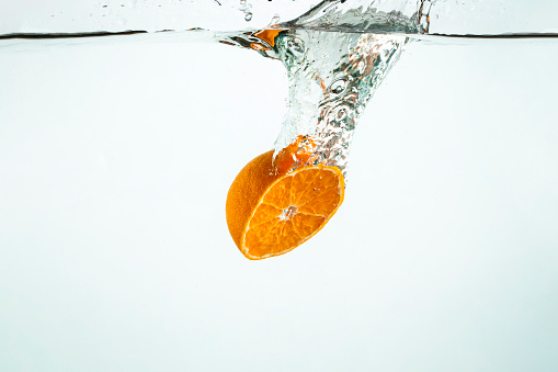 A close-up shot of half an orange being dropped into water.