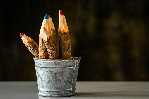 A close-up shot of a metal pot filled with coloured wooden pencils.