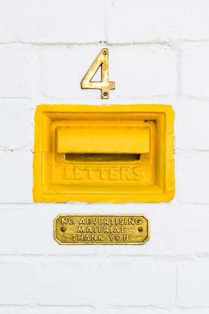 Photo of House number, letter box and 'no advertising material' sign on white painted brick wall