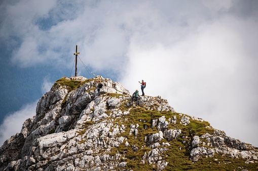 Two climbers going up the hill with a cross on the summit