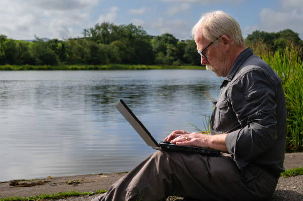 istock Senior man sitting outside looking at a laptop 1418224564