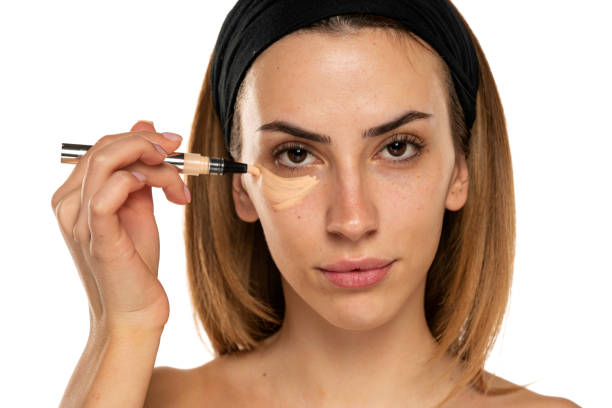istock Young woman applyes concealer under her eyes 1418224829