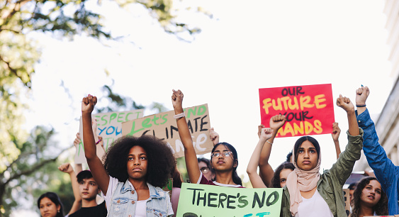 Multiethnic youth activists standing up against climate change. Group of teenagers marching against global warming and pollution. Diverse young people joining the global climate strike.