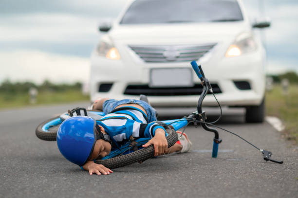 a boy was injured because his bicycle collided with a car on the road. asian boy was hit by car. the concept of road accidents and reduction of accidents from use of cars on the road. selective focus. - child bicycle cycling danger imagens e fotografias de stock