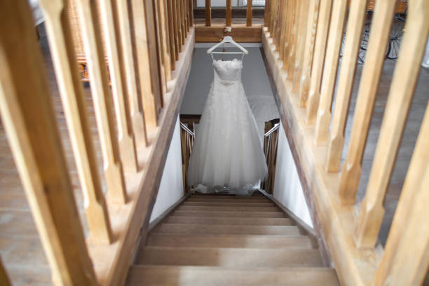 Wedding dress hangs over a wooden staircase.