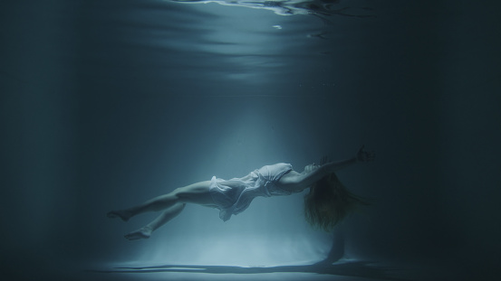 girl in a white dress swims underwater in 4k