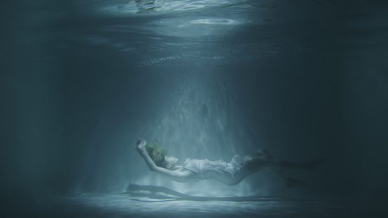 a girl in a white dress falls under the water in 4k