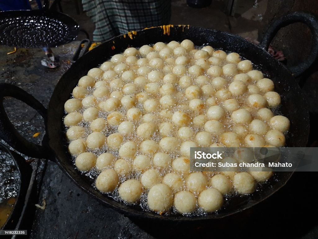 An Indian sweet Gulab Jamun. Gulab Jamun, an Indian sweet is being made in a sweet shop.  This sweet is being fried in hot oil.  It is then dipped in sugar syrup. A popular indian sweet. Traditional sweet of india. Celebration Stock Photo