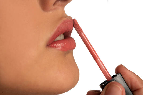 istock woman applying a lip gloss on her lips 1418234124