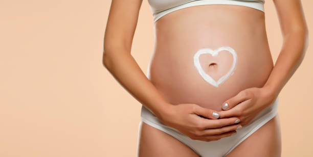 Heart shape drawn on pregnant woman's belly stock photo