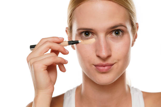 istock Young blond woman applying concealer under her eyes 1418235605