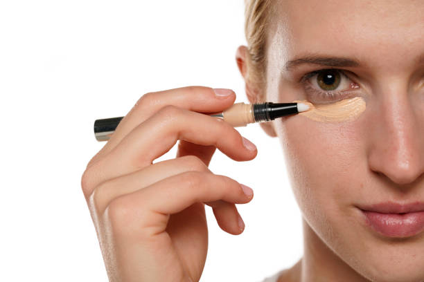 istock Half portrait of a young blond woman applying concealer under her eyes 1418235607