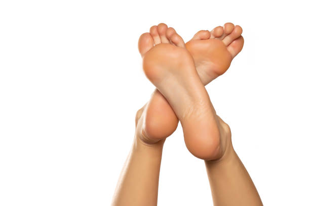 istock Beautiful woman's bare crossed feet against a white background 1418237329