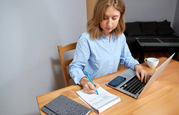 istock Young happy woman sitting at desk, working on computer at home. 1418238816