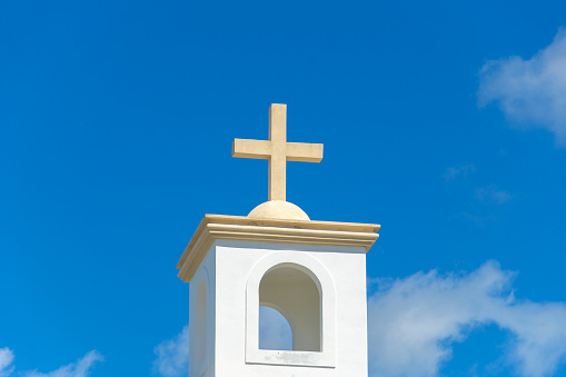 Concrete christian cross against a blue sky - concept image with copy space. Stone cross on the roof of the Catholic Church.