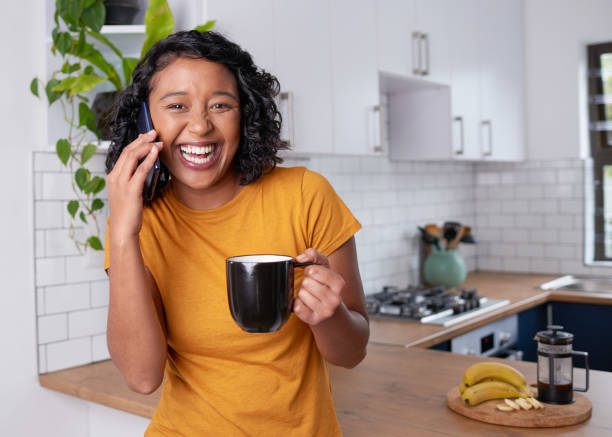 istock A young multi-ethnic woman laughs while on the phone in kitchen 1418240807